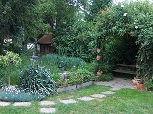Wiese im Garten mit Gehweg und Beet im Hintergrund
