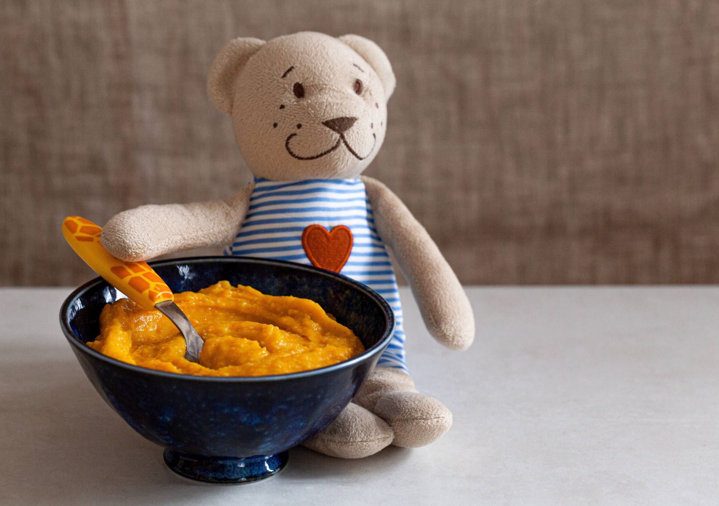 Teddybär neben einer Schüssel Babybrei