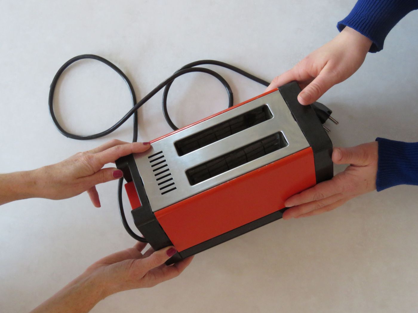 Zwei paar Hände, die einen Toaster halten.
