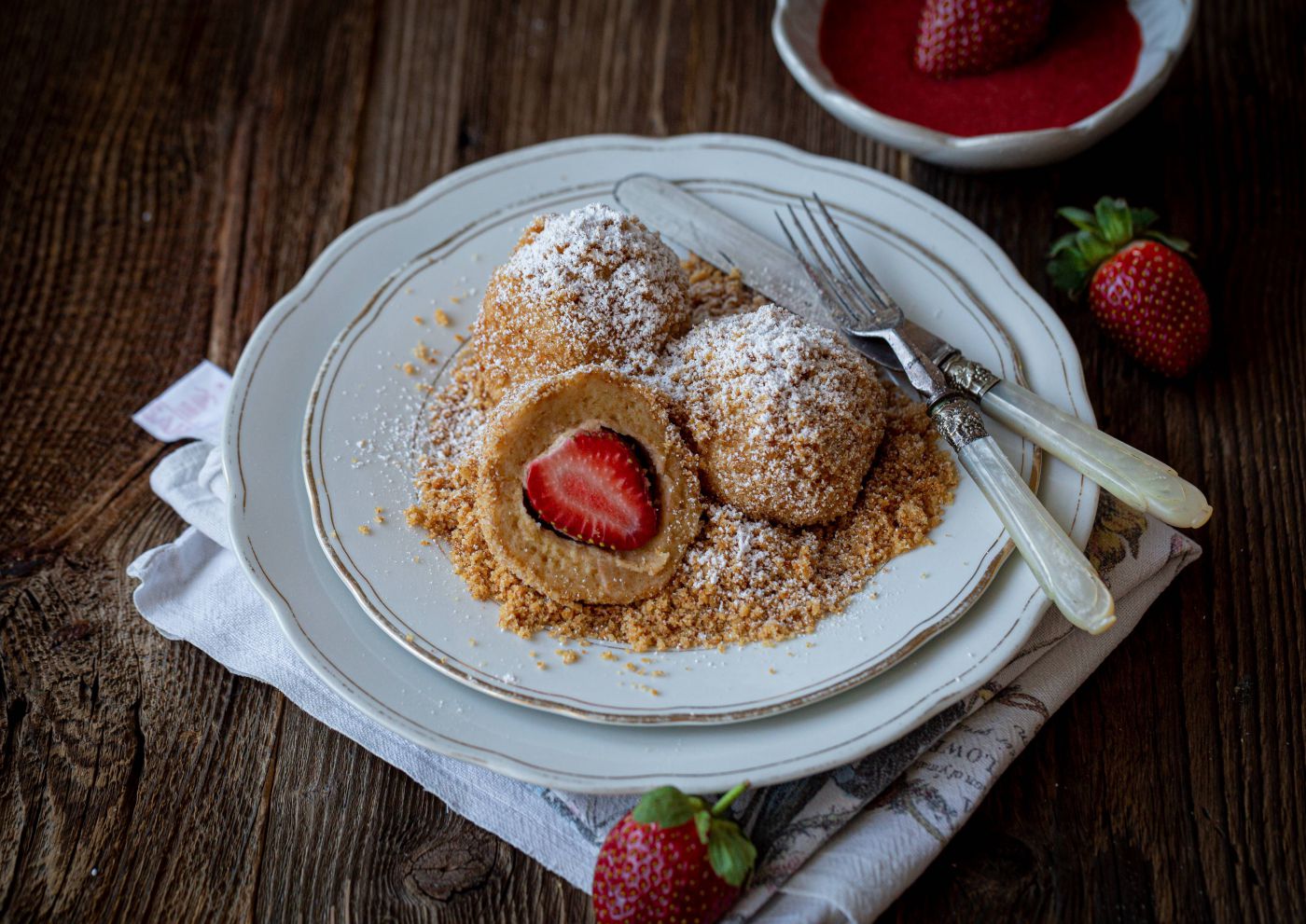 Drei Erdbeerknödel mit Brotbrösel und Puderzucker