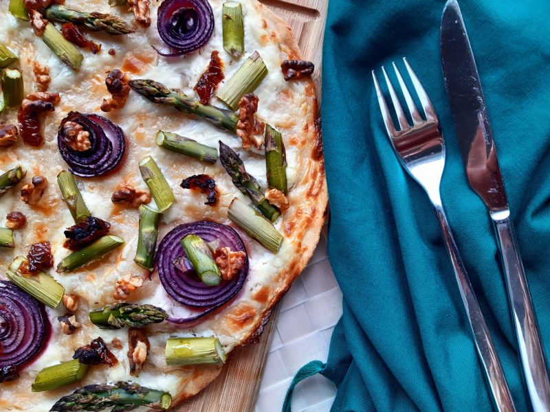 Flammkuchen mit Spargel auf einem Brett