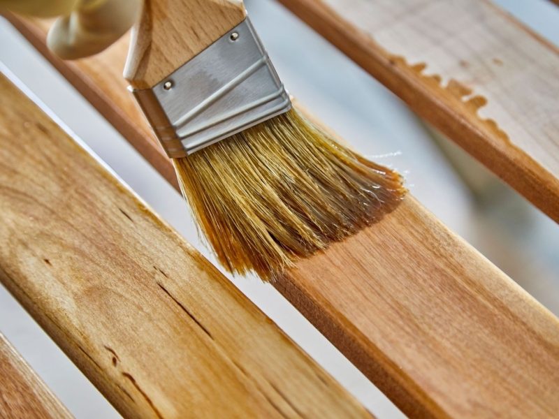 ein Pinsel mit Holzlasur auf einem Holzbrett