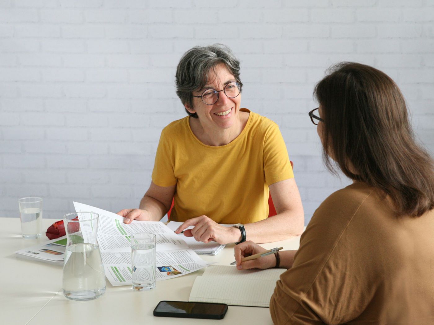 Zwei Frauen sitzen an einem Tisch und führen ein Gespräch.