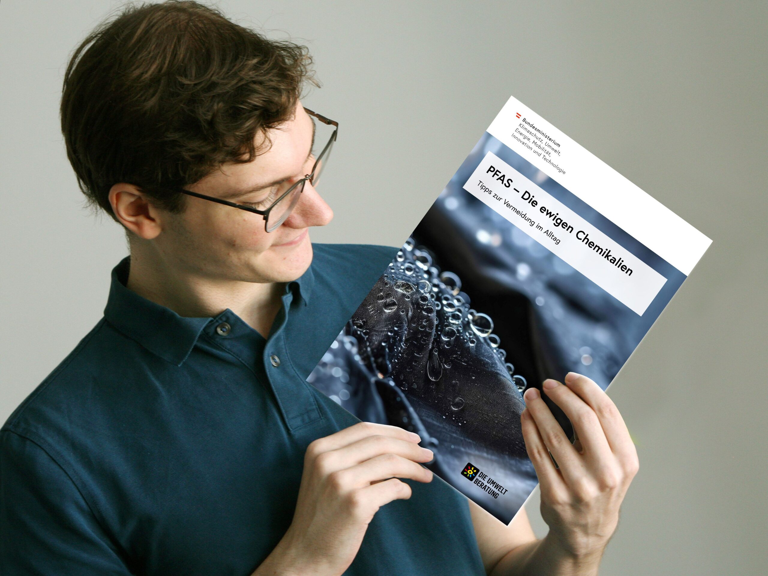 Junger Mann zeigt die PFAS-Broschüre