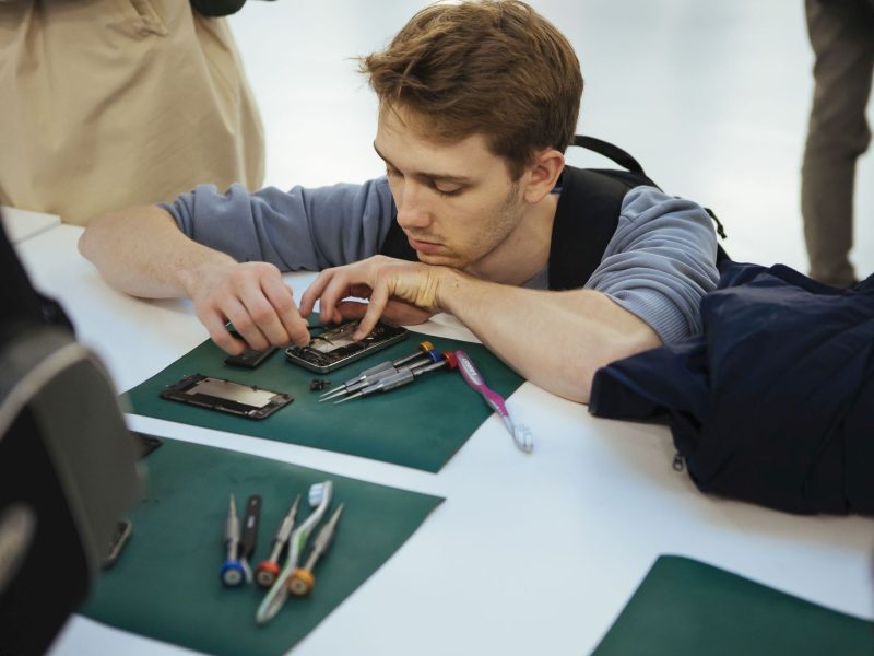 Junger Mann repariert Handy