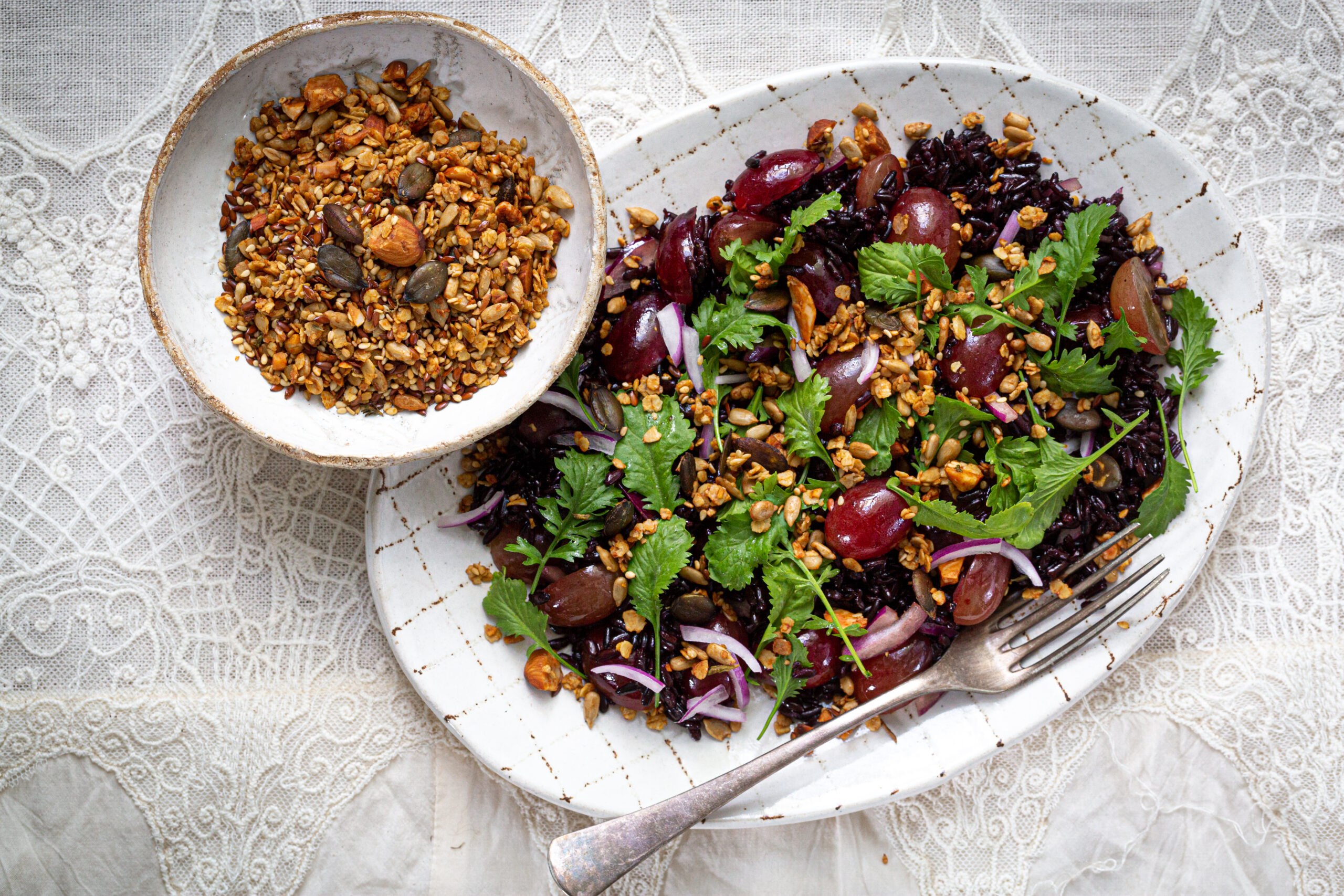 ein großer Teller gefüllt mit dem Salat aus schwarzen Reis, Ruccola, frischen Weintrauben und dem salzigen Granola