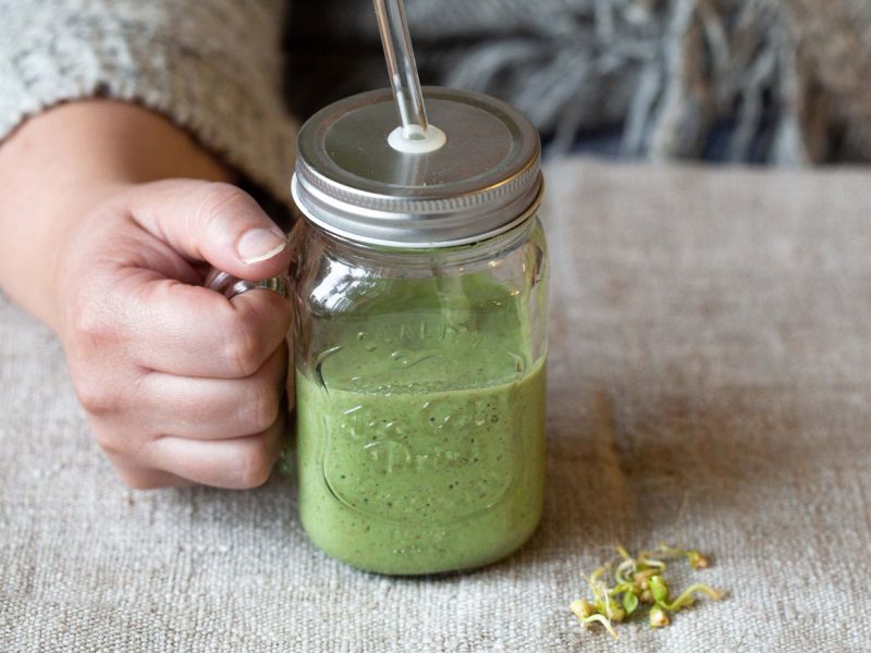 grüner Smoothie in einem Glas mit Strohhalm