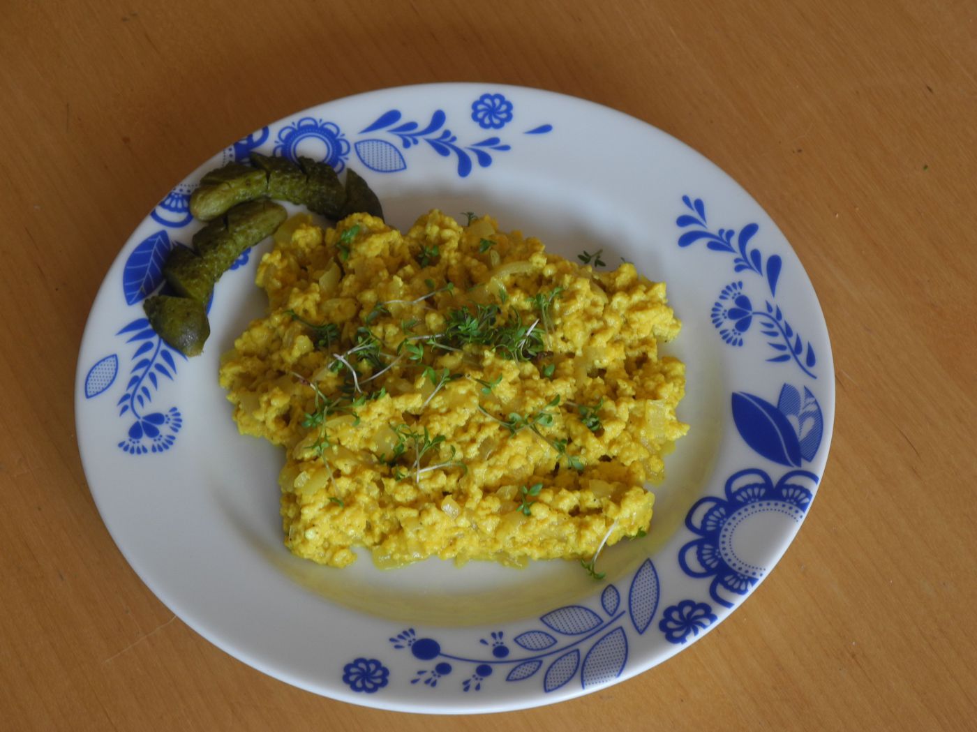 Vegane Eierspeis auf Teller mit frischen Kräutern und Essiggurke
