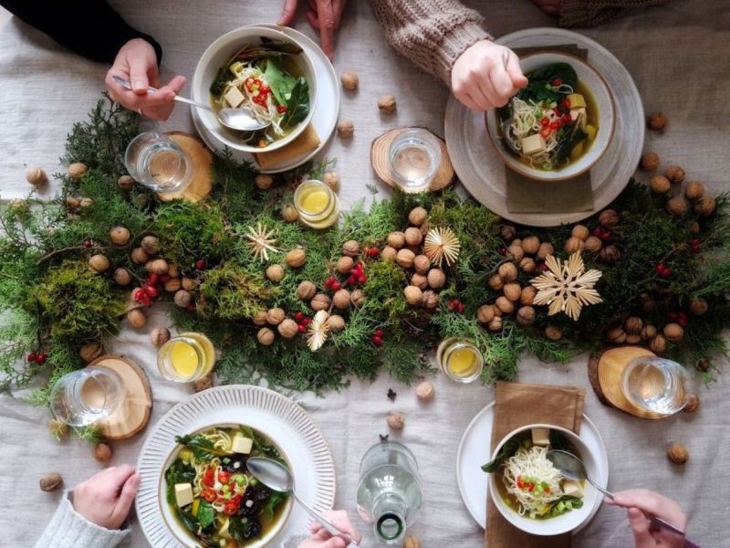 vier Menschen sitzen an einem festlichen Tisch und essen Suppe