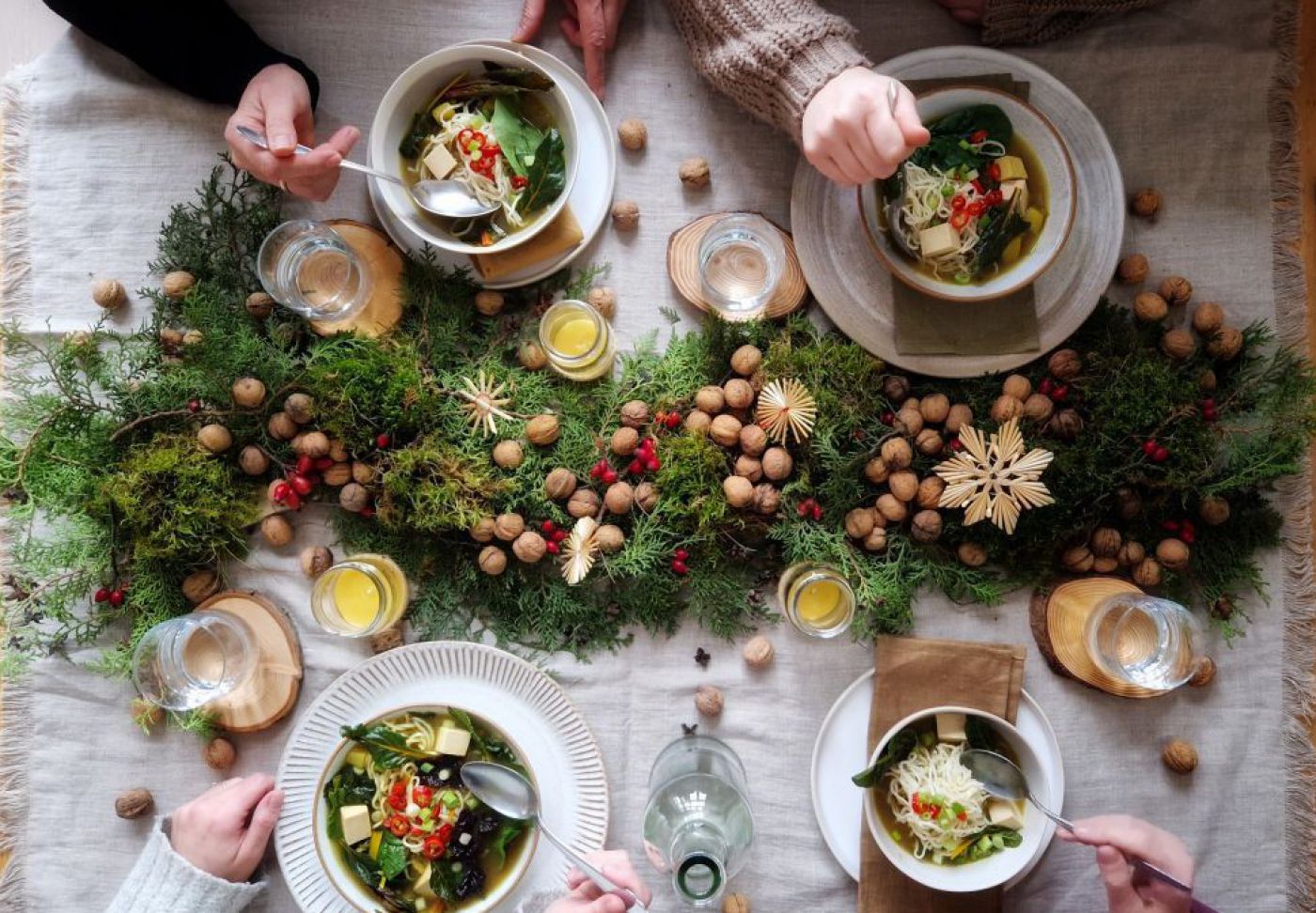 vier Menschen sitzen an einem festlichen Tisch und essen Suppe