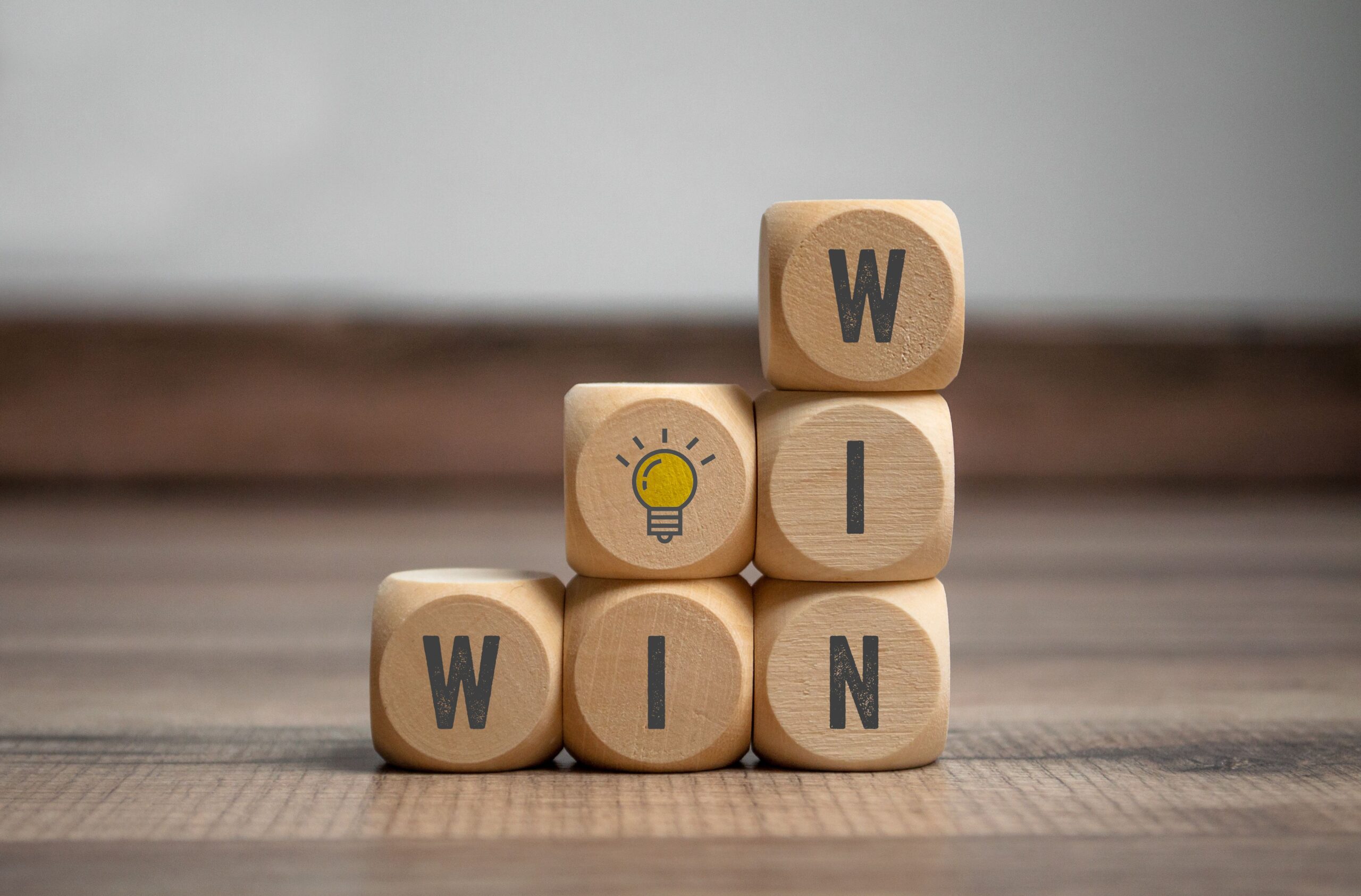 Holzwürfel mit den Buchstaben WinWin darauf und Glühbirne